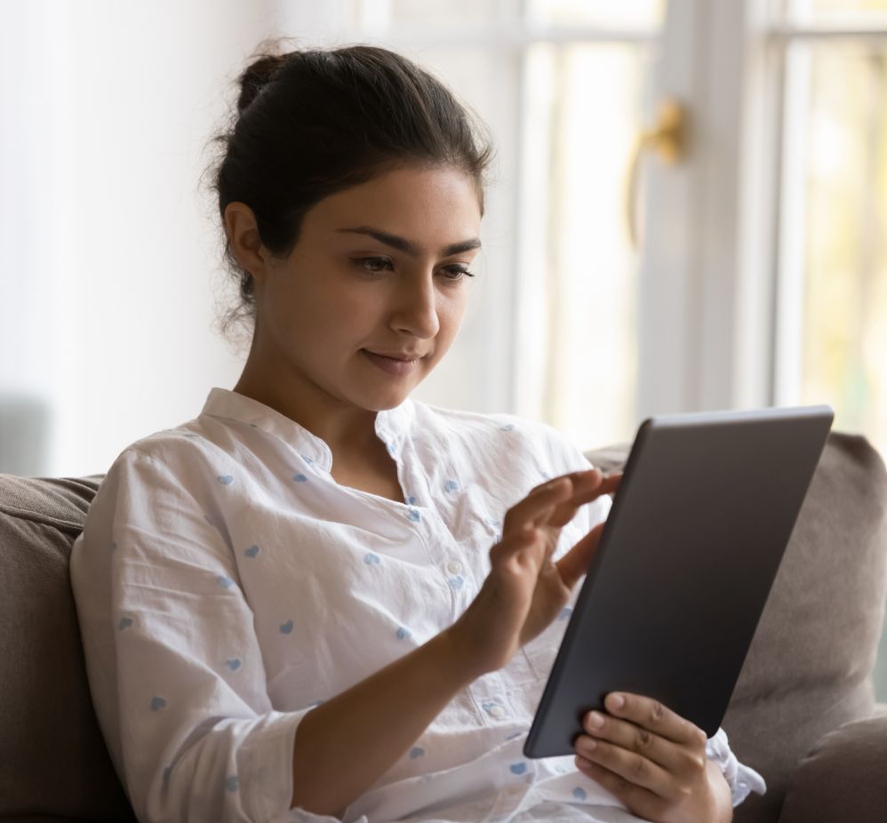 woman sitting on couch reading tablet