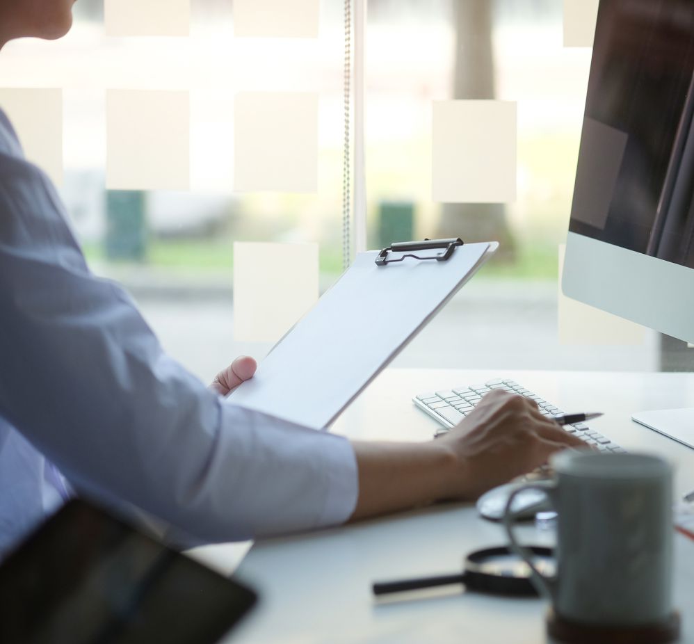 man holding clipboard looking at monitor