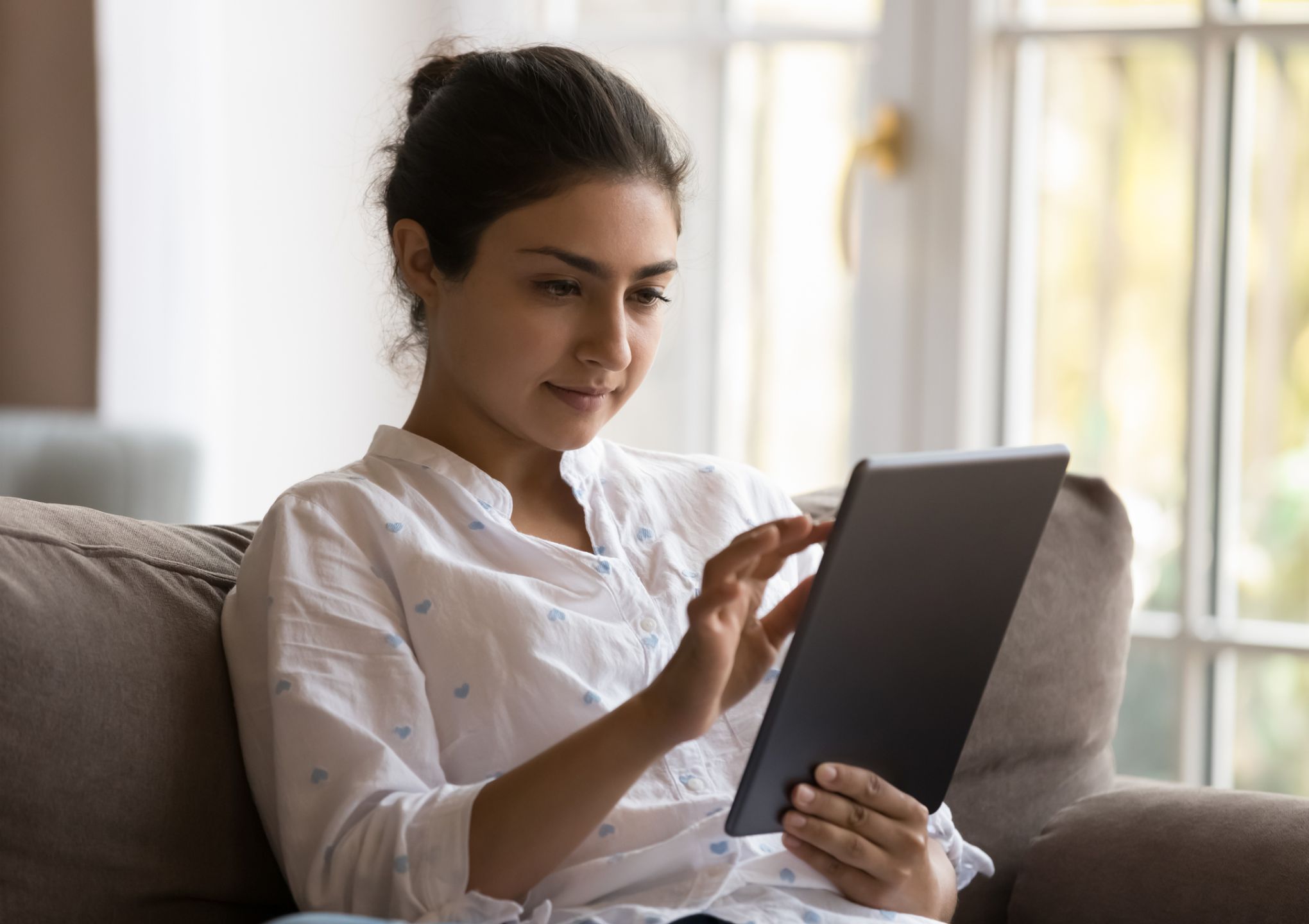 woman sitting on couch reading tablet